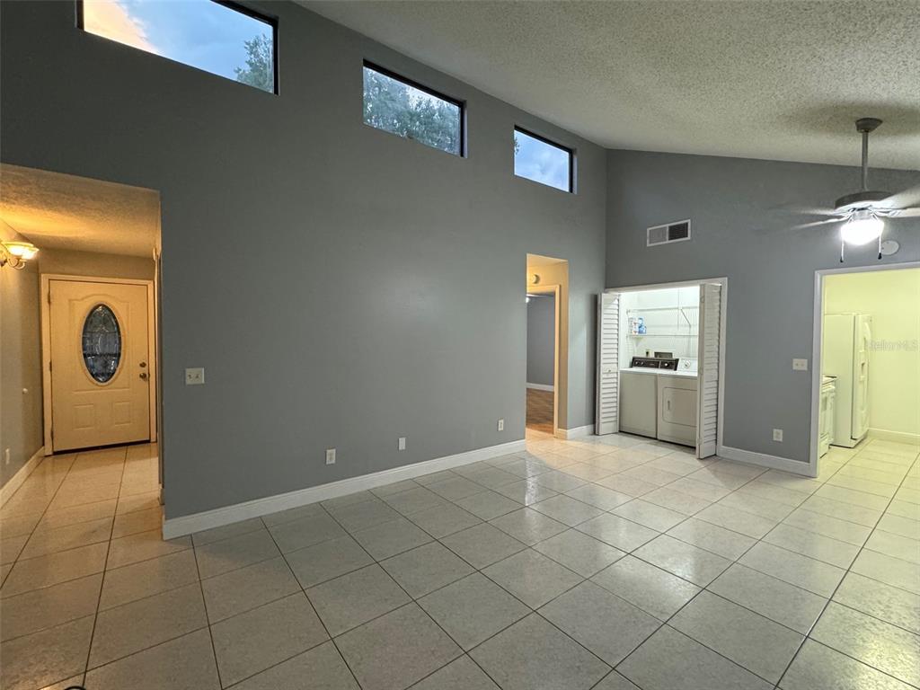 A living room with gray walls, tile flooring, vaulted ceilings, and a laundry closet — 2304 INAGUA WAY UNIT 2304, WINTER PARK, FL