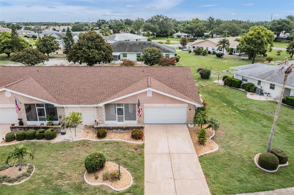 An aerial view of a single-story duplex with a brown shingled roof and concrete driveway — 1209 WILD FEATHER LANE, SUN CITY CENTER, FL