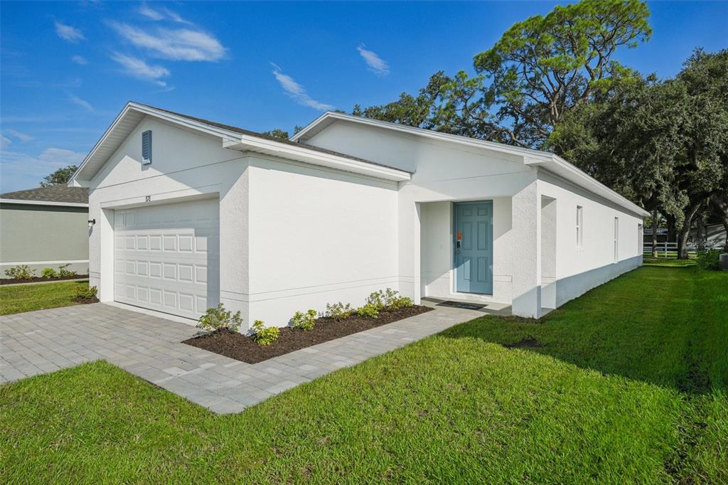 A white single-story house features a two-car garage, a blue front door, and paver driveway — 2514 CARDAMOM COURT, HAINES CITY, FL