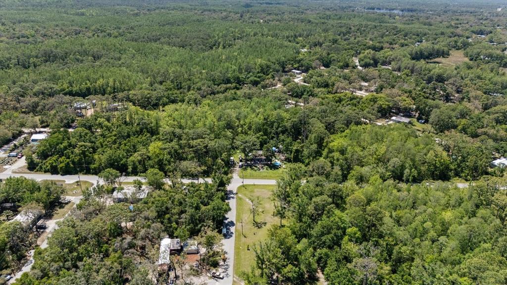 An aerial view shows a rural residential area with houses surrounded by dense forest — 12914 MIDVALE AVENUE, NEW PORT RICHEY, FL