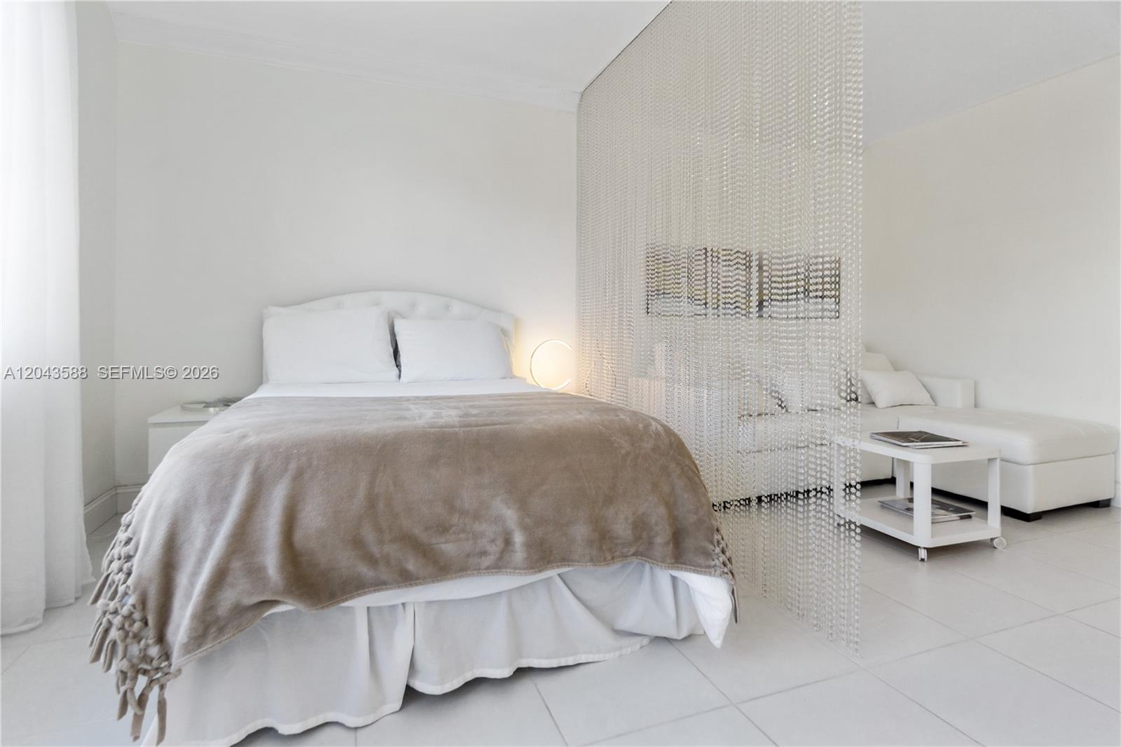 A bedroom with a bed and a beaded room divider separating it from a lounge — 100 Lincoln Rd # 306, Miami Beach FL 33139, MIAMI BEACH, FL