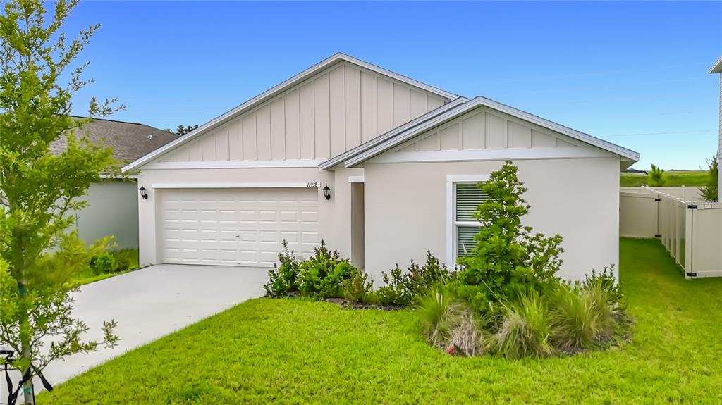 A single-story house with a beige stucco exterior, a two-car garage, and a front lawn — 11938 BRAE, DADE CITY, FL