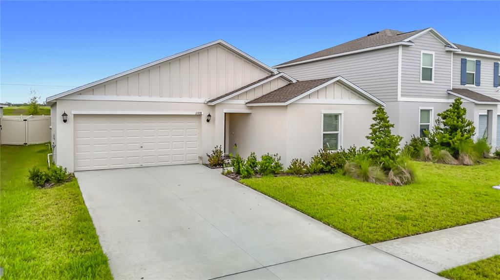 A single-story house with a beige stucco exterior, a two-car garage, and a front lawn — 11938 BRAE, DADE CITY, FL