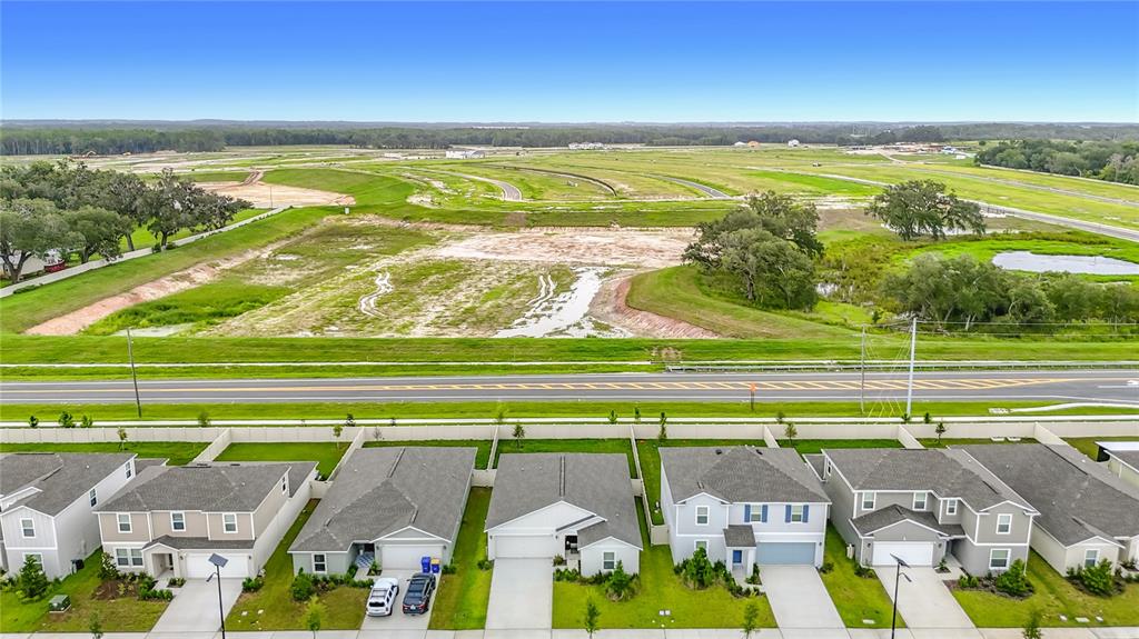 An aerial view shows a row of suburban houses facing a road and open land — 11938 BRAE, DADE CITY, FL