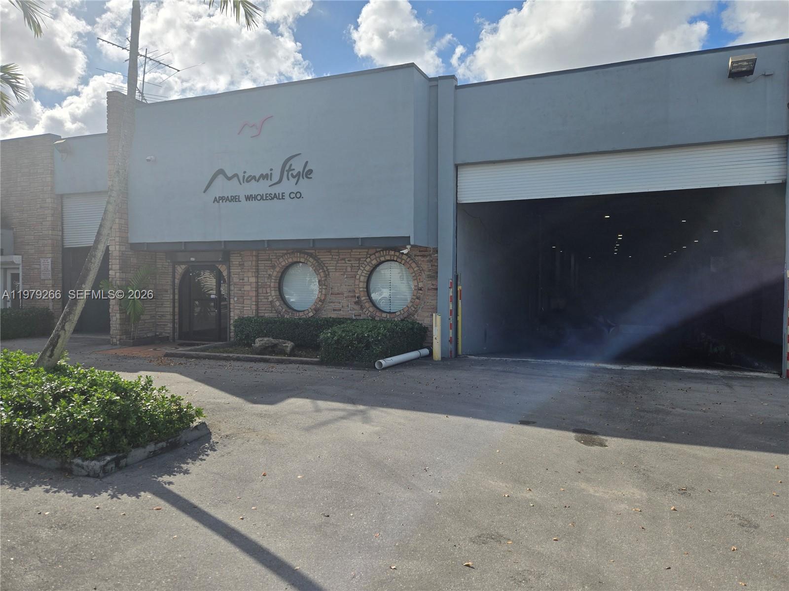 The exterior of a commercial building features a gray facade, brick accents, and a warehouse bay — 7480 NW 52nd St, Miami FL 33166, MIAMI, FL