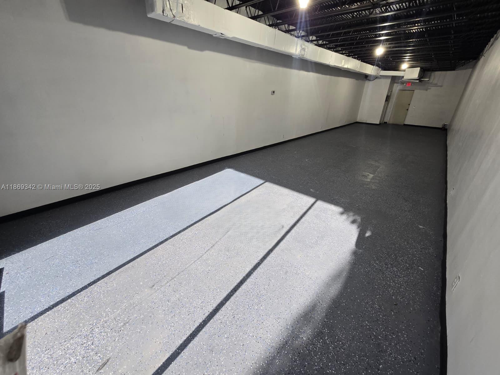An empty rectangular room features white walls, a dark speckled floor, and an exposed ceiling — 2501 N State Road 7 # 2533, Margate FL 33063, MARGATE, FL