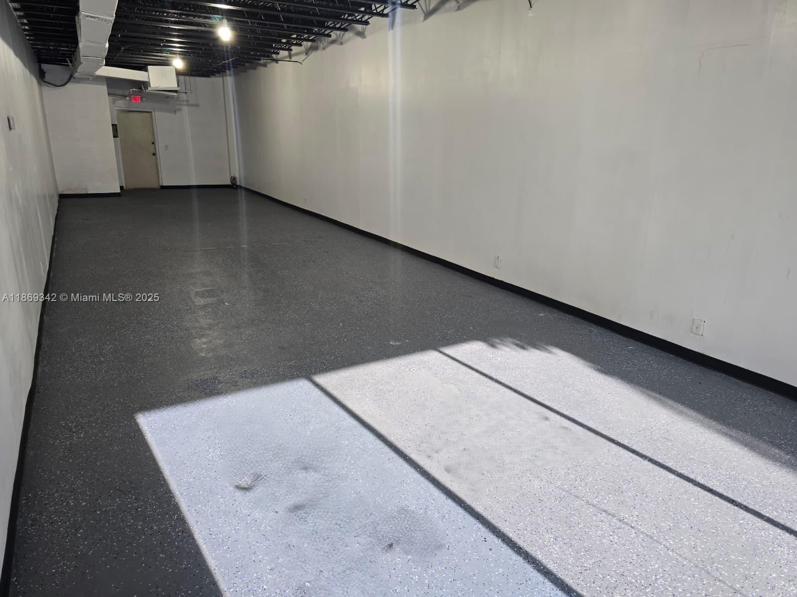 An empty commercial space features white walls, a dark speckled floor, and exposed ceiling joists — 2501 N State Road 7 # 2533, Margate FL 33063, MARGATE, FL