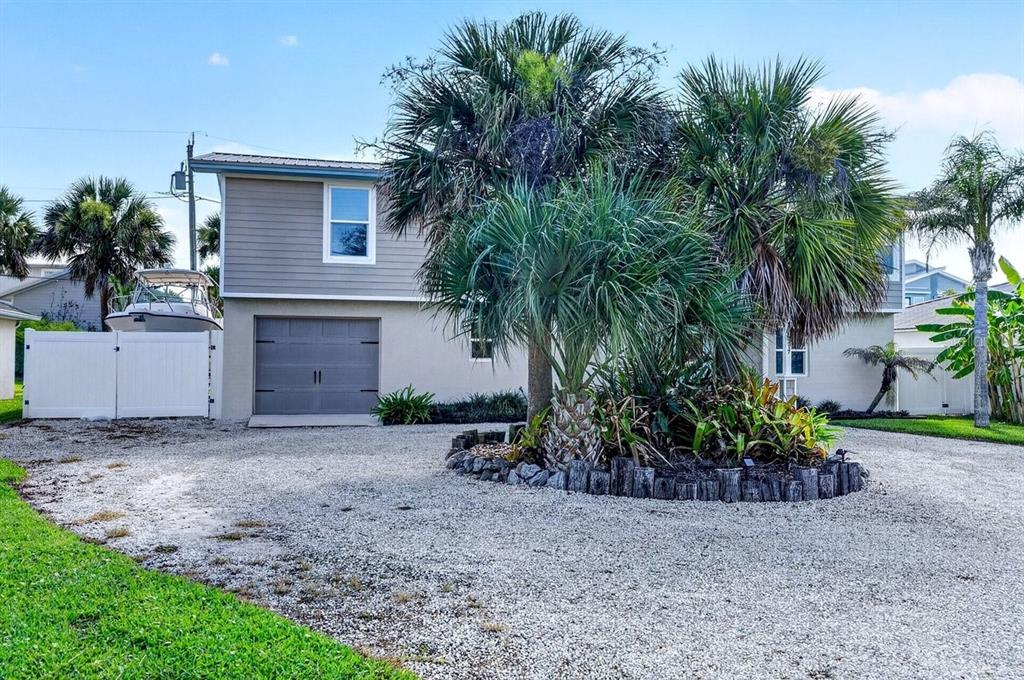 A two-story house with a gravel driveway, a garage, and palm trees in the yard — 4717 S ATLANTIC AVENUE, NEW SMYRNA BEACH, FL