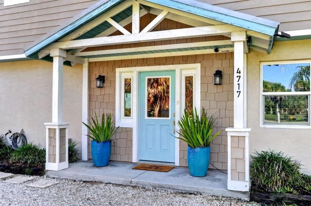 A light blue front door sits under a covered porch with two large blue planters — 4717 S ATLANTIC AVENUE, NEW SMYRNA BEACH, FL