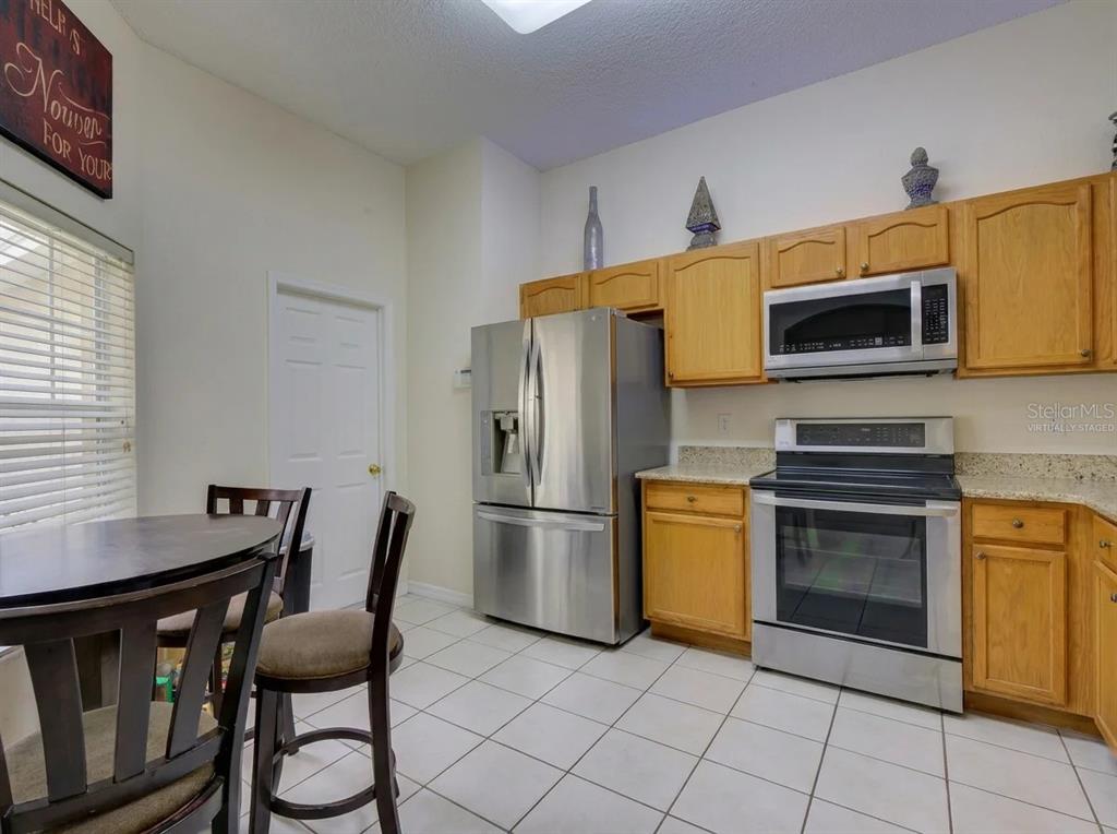 A kitchen features light wood cabinets, stainless steel appliances, and a small dining table — 1804 LAKE VILLA DRIVE, TAVARES, FL