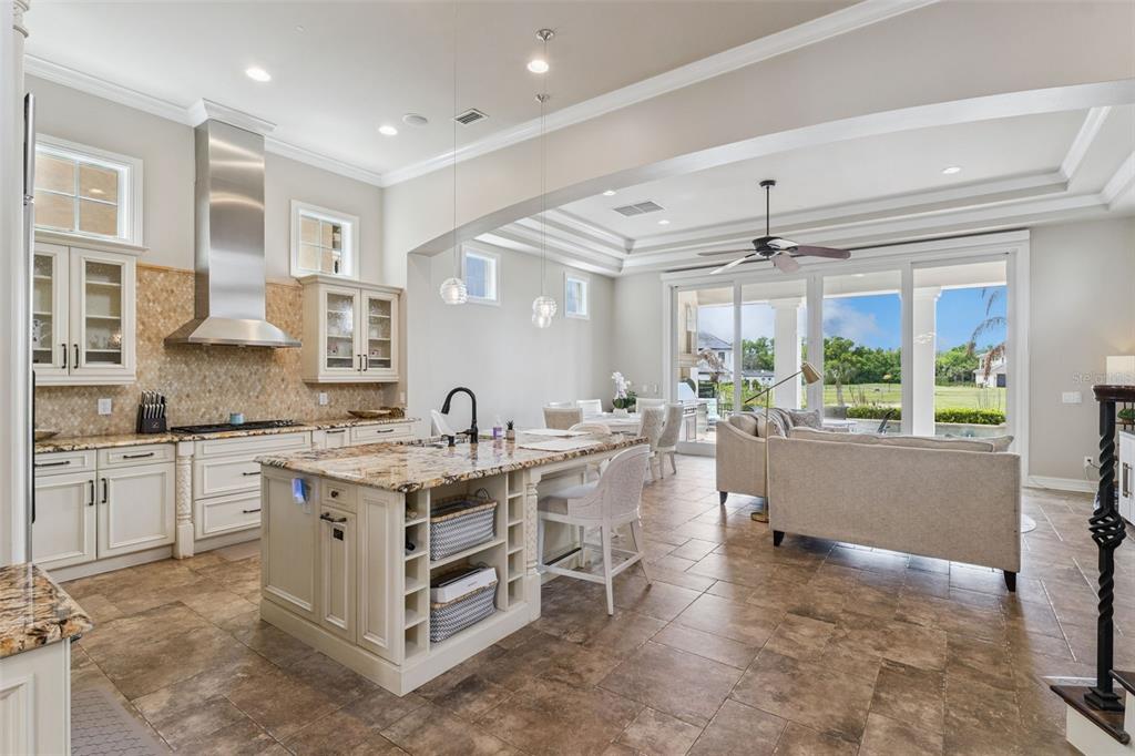A kitchen with granite countertops and a central island overlooks a living and dining area — 1172 CASTLE PINES CT, REUNION, FL