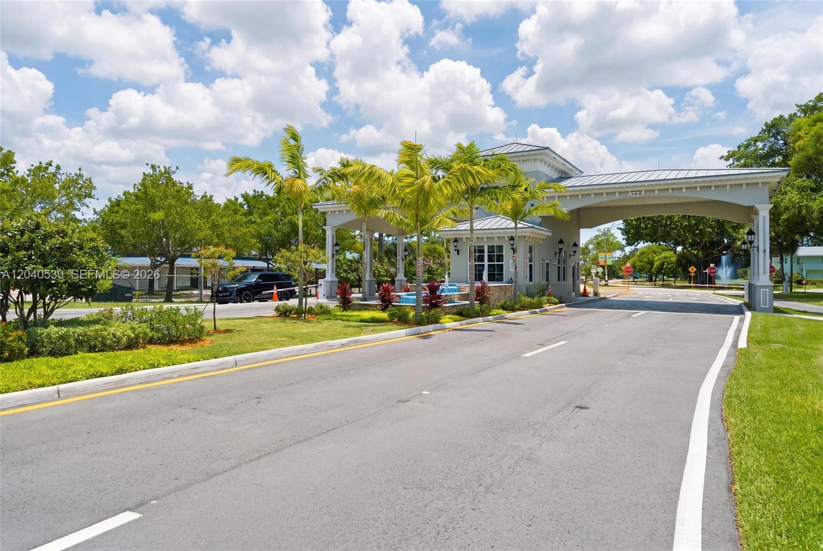 A gated community entrance features a guardhouse, palm trees, and a paved driveway — 4001 Ashby C # 4001, Deerfield Beach FL 33442, DEERFIELD BEACH, FL