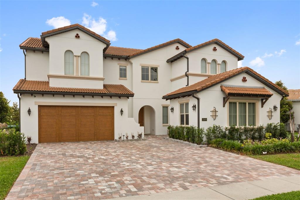 A two-story Mediterranean-style house features a tiled roof, white stucco walls, and a paver driveway — 15499 SHOREBIRD LANE, WINTER GARDEN, FL