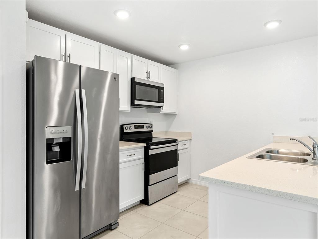 A kitchen features white cabinets, stainless steel appliances, and light-colored countertops — 12168 GROSSPOINT AVENUE, PORT CHARLOTTE, FL