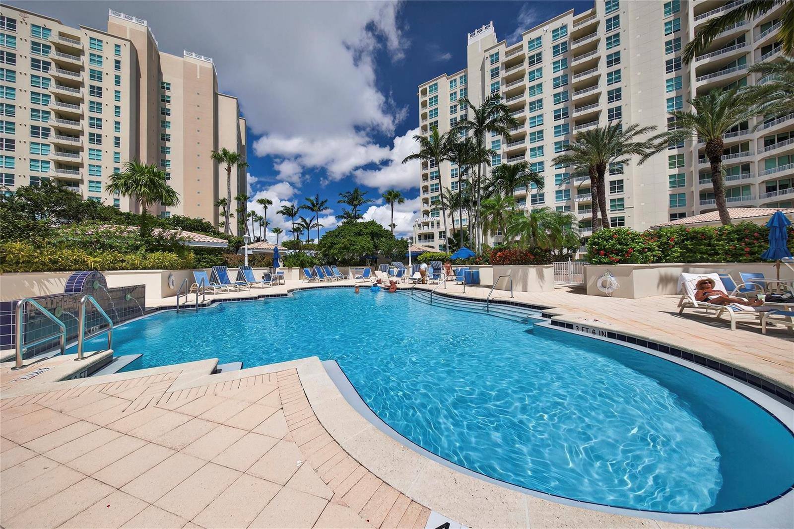 A swimming pool with lounge chairs and palm trees sits between two large apartment buildings — 3700 S Ocean Boulevard # 308, Highland Beach FL 33487, HIGHLAND BEACH, FL