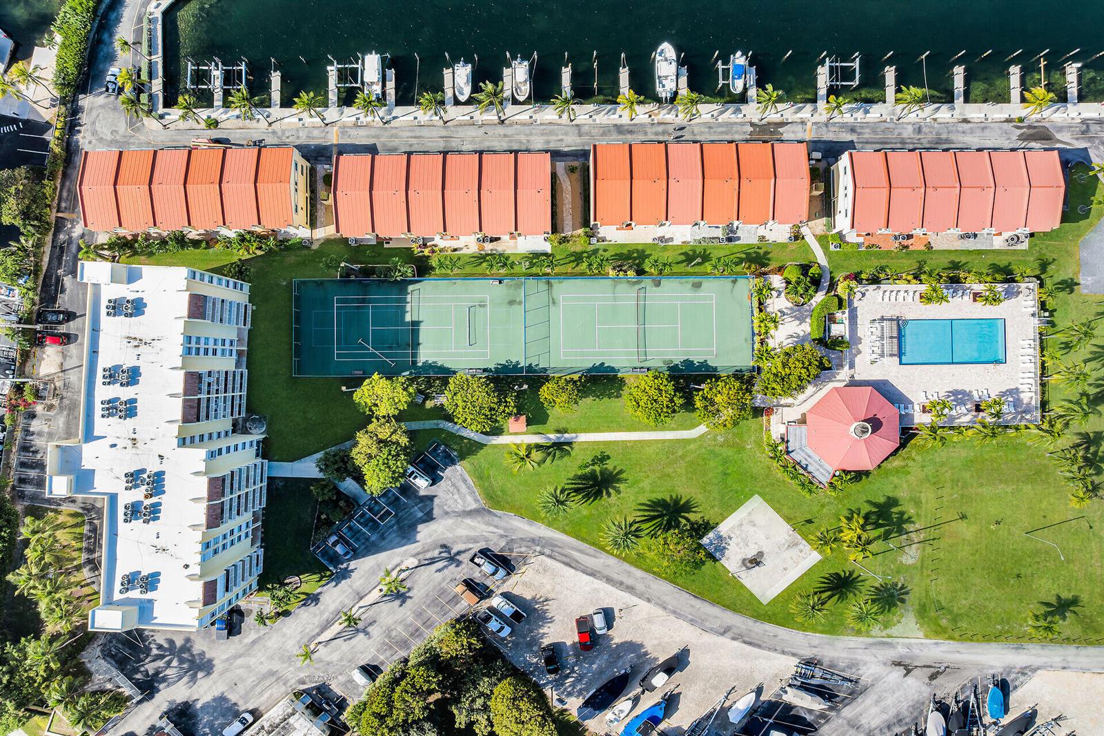 Aerial view of a residential complex with tennis courts, a swimming pool, and boat slips — 88540 Overseas Highway # 304, Tavernier FL 33070, TAVERNIER, FL