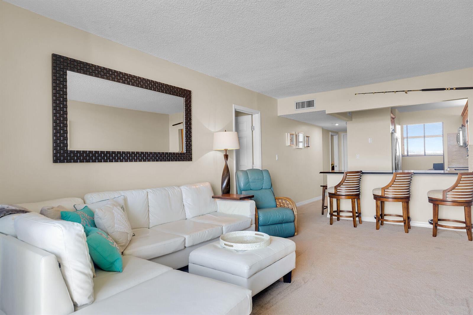 A living room features a white sectional sofa, a blue recliner, and a kitchen breakfast bar — 88540 Overseas Highway # 304, Tavernier FL 33070, TAVERNIER, FL