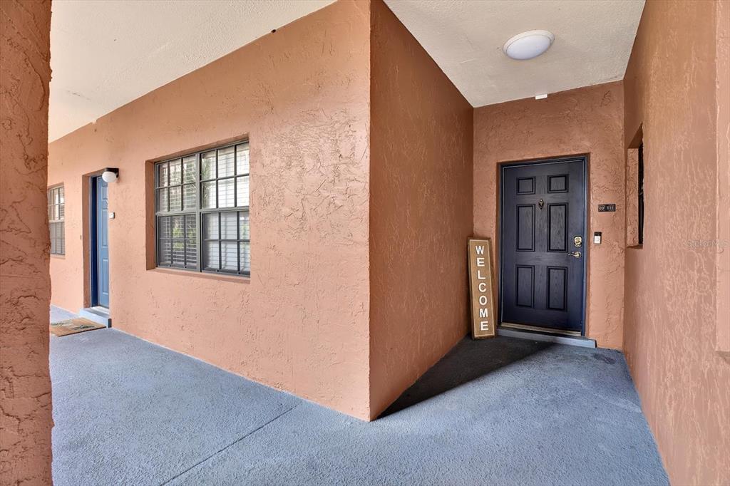 An exterior view of a covered entryway with a dark door and a welcome sign — 6100 GULFPORT BOULEVARD S UNIT 111, GULFPORT, FL