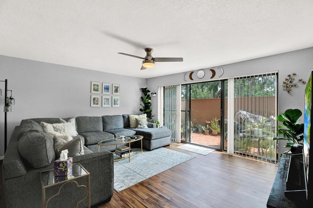 A living room features a gray sectional sofa, a ceiling fan, and sliding glass patio doors — 6100 GULFPORT BOULEVARD S UNIT 111, GULFPORT, FL