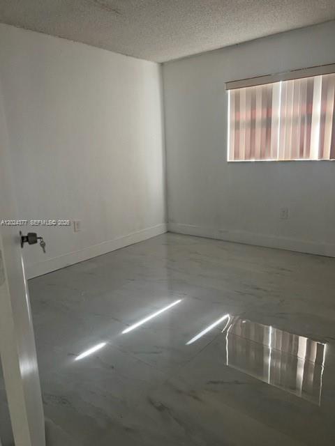 An empty bedroom features white walls, a window with vertical blinds, and glossy tile flooring — MIAMI, FL