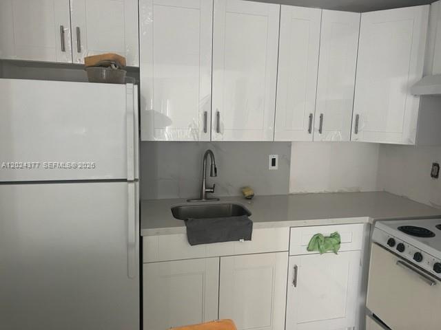 A kitchen features white shaker-style cabinets, a stainless steel sink, and white appliances — MIAMI, FL