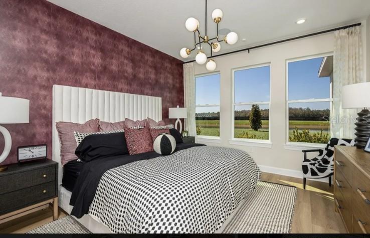 A bedroom features a deep red accent wall, a white tufted headboard, and large windows — 7717 BLUE MOON RUN, SARASOTA, FL