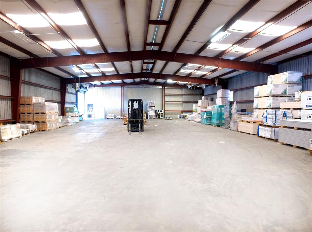 A large warehouse interior features concrete floors, exposed steel beams, and stacks of building materials — 4500 CARMICHAEL AVENUE UNIT Building 2, SARASOTA, FL