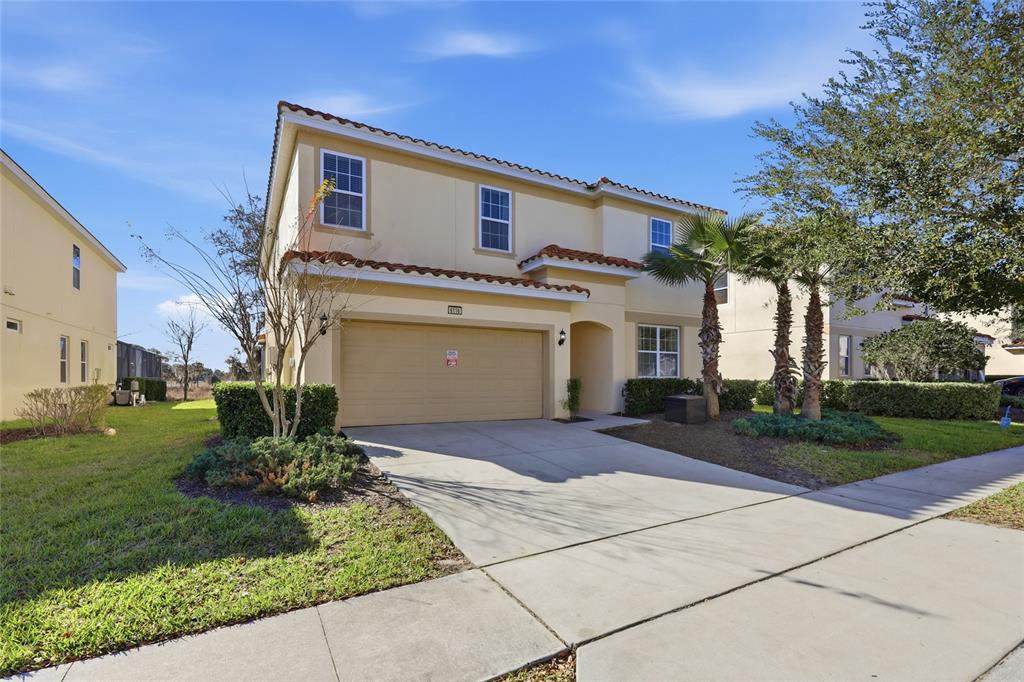 A two-story, beige stucco house with a two-car garage and a tile roof — 6116 BROAD OAK DRIVE, DAVENPORT, FL