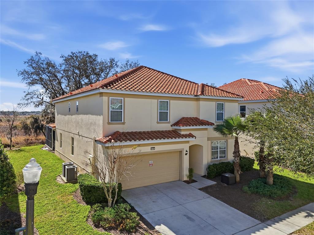 A two-story stucco house with a tile roof and an attached garage — 6116 BROAD OAK DRIVE, DAVENPORT, FL