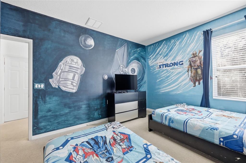 A bedroom with Star Wars-themed wall murals, two twin beds, and a black dresser — 6116 BROAD OAK DRIVE, DAVENPORT, FL