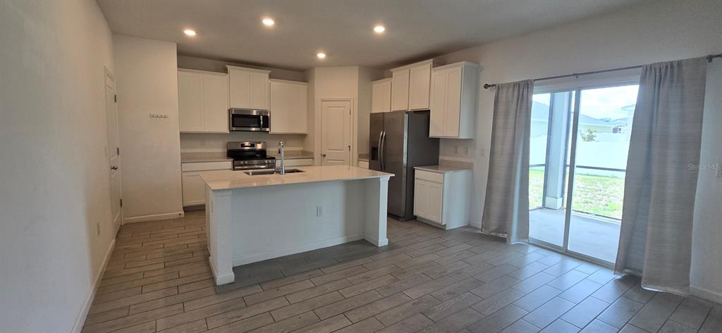 A kitchen features white cabinets, stainless steel appliances, a center island, and tile flooring — 3980 NE 34TH AVENUE, OCALA, FL
