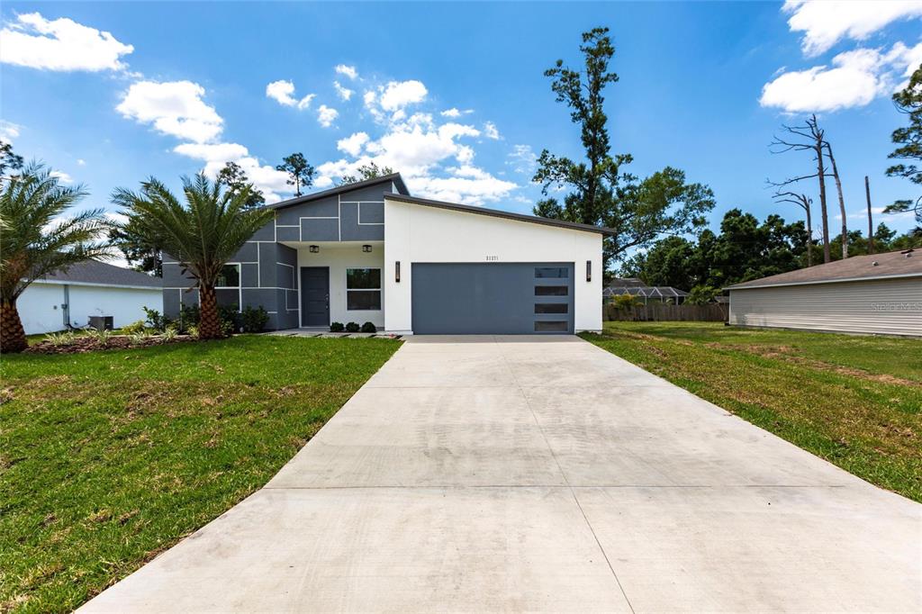 A modern single-story house features a gray and white exterior with a concrete driveway — 221 DORMAN STREET, PORT CHARLOTTE, FL