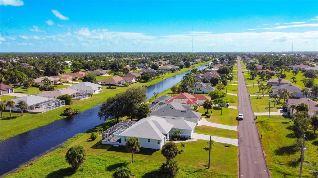 An aerial view of a suburban neighborhood featuring houses along a canal and a road — 202 LONG MEADOW LANE, ROTONDA WEST, FL