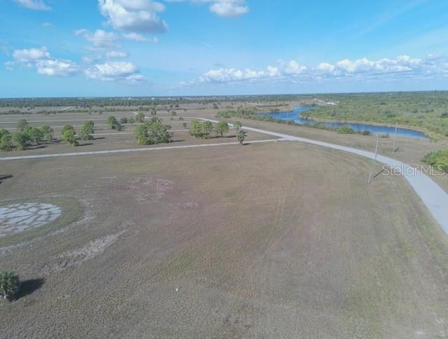 An aerial view shows a large, undeveloped grassy lot next to a road and water — 12455 BLUE MARLIN ROAD, PLACIDA, FL