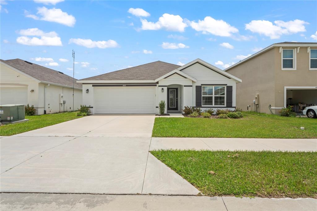 A single-story suburban house with a two-car garage, white siding, and a concrete driveway — 4041 AUTUMN AMBER, SPRING HILL, FL