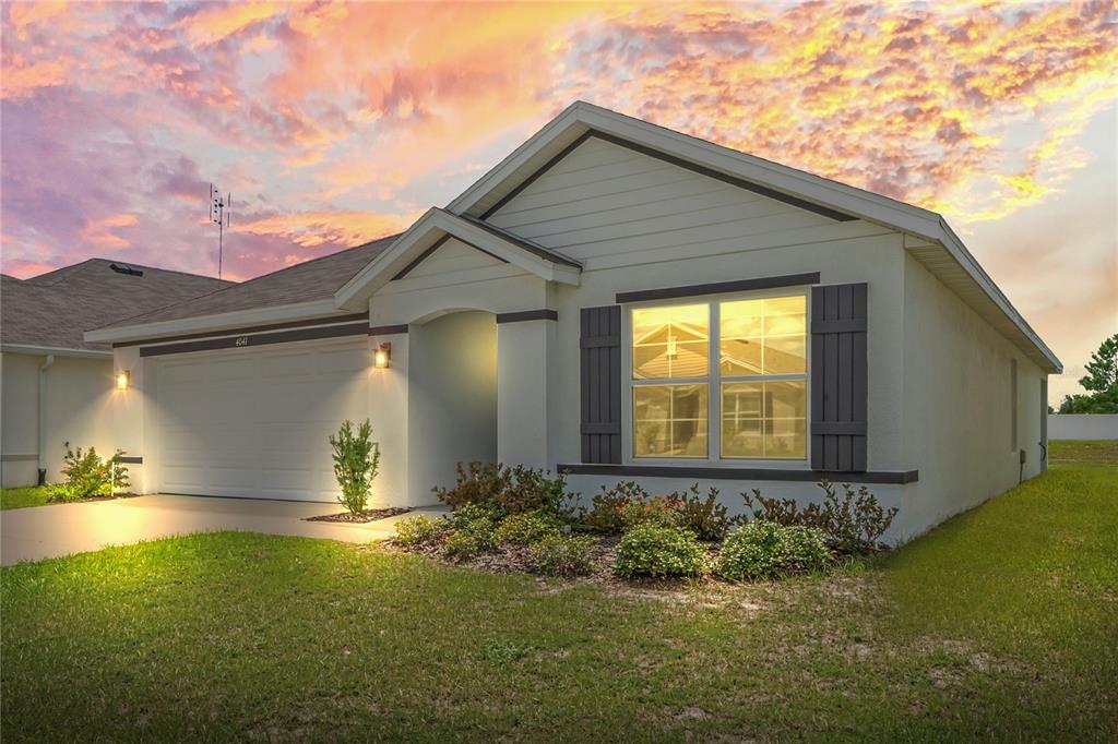 A single-story house with a white stucco exterior, dark shutters, and a two-car garage — 4041 AUTUMN AMBER, SPRING HILL, FL