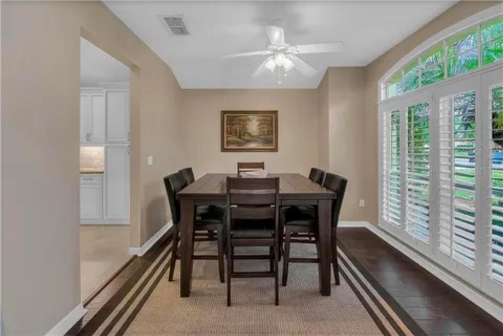 A dining room with a dark wood table, chairs, ceiling fan, and plantation shutters — 624 HARDWOOD CIRCLE, ORLANDO, FL