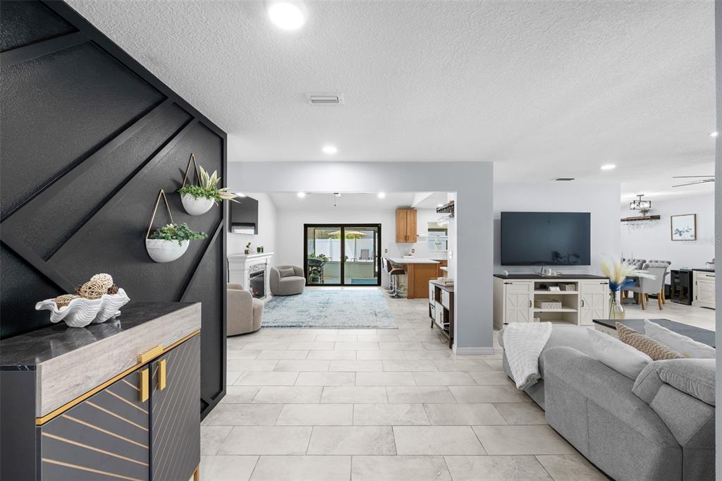 A modern open-concept living area features a black accent wall, tile flooring, and neutral furnishings — 14018 CASCADE LANE, TAMPA, FL