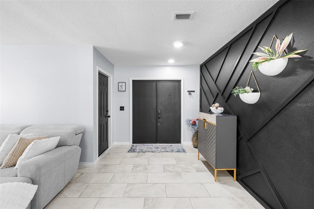 An entryway features a black accent wall with geometric molding, a console table, and double doors — 14018 CASCADE LANE, TAMPA, FL