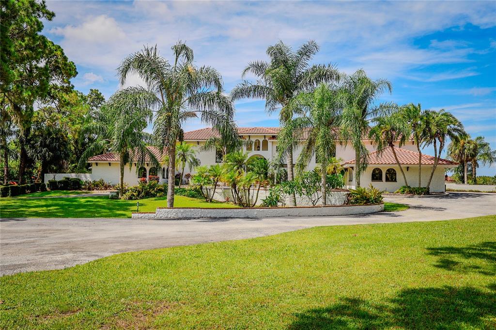 A large, two-story stucco house with a tile roof sits behind a curved driveway — 500 N HIGHLAND AVENUE, TARPON SPRINGS, FL