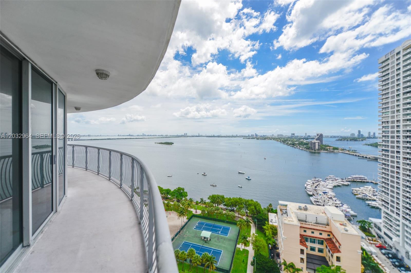 A curved balcony overlooks a bay, a marina, tennis courts, and a high-rise building — 1750 N Bayshore Dr # 2402, Miami FL 33132, MIAMI, FL