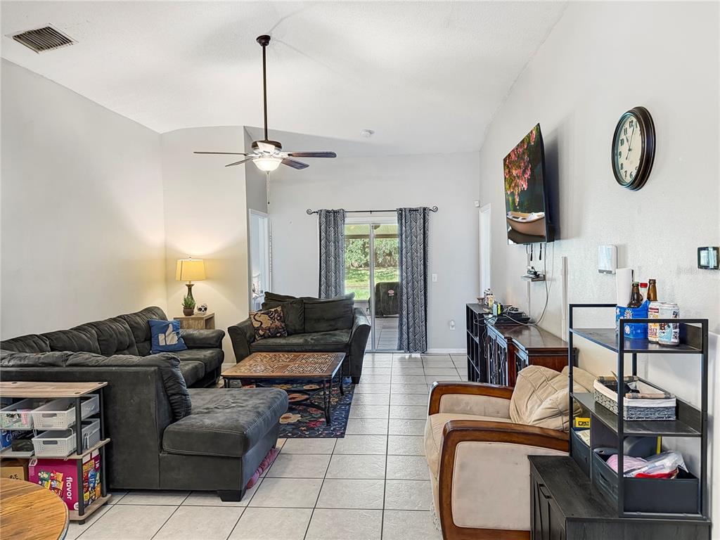 A living room features tile floors, a dark sectional sofa, a ceiling fan, and a television — 3012 SUMMER HOUSE DRIVE, VALRICO, FL
