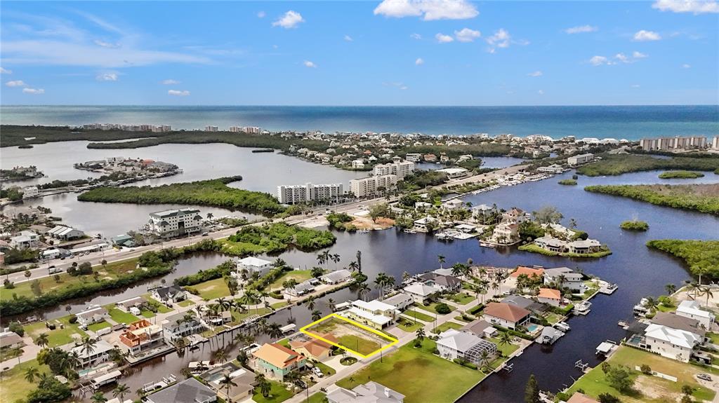 An aerial view shows a vacant waterfront lot outlined in yellow within a residential neighborhood — 4851 & 4853 REGAL DR, BONITA SPRINGS, FL