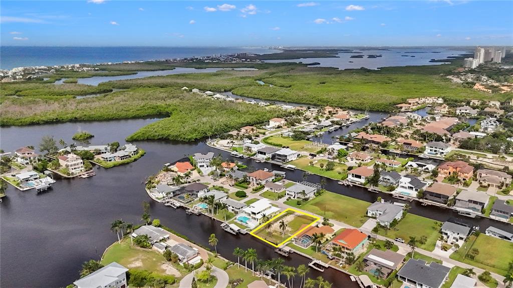 An aerial view shows a vacant waterfront lot outlined in yellow within a residential neighborhood — 4851 & 4853 REGAL DR, BONITA SPRINGS, FL