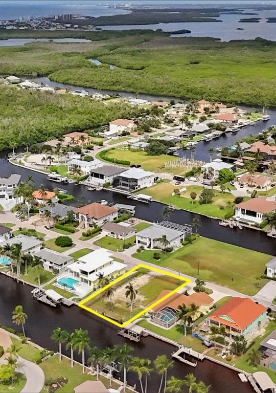 An aerial view shows a vacant waterfront lot highlighted in yellow within a residential neighborhood — 4851 & 4853 REGAL DR, BONITA SPRINGS, FL
