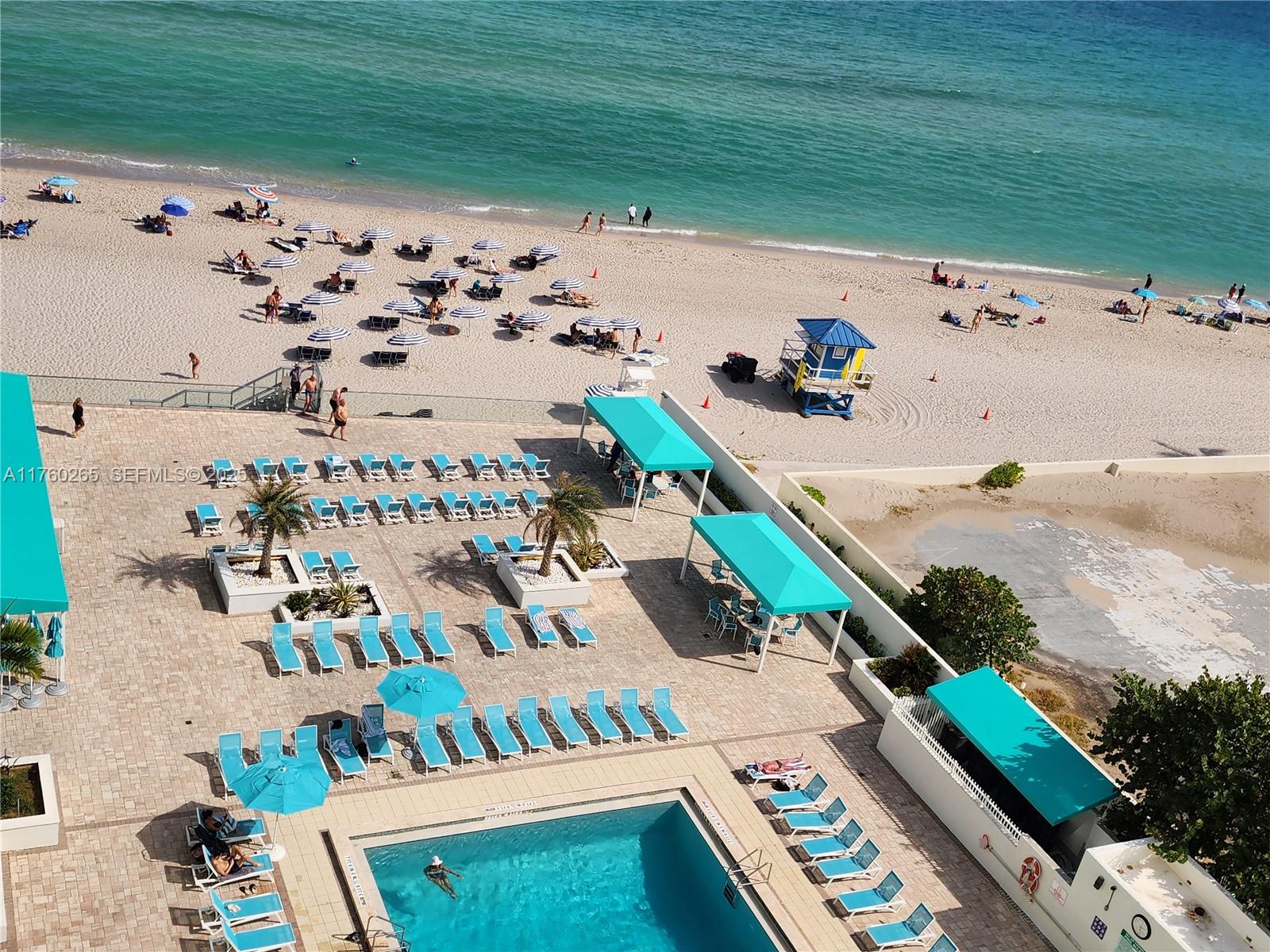 An aerial view shows a swimming pool deck with lounge chairs and a beach beyond — 3725 S Ocean Dr # 1008, Hollywood FL 33019, HOLLYWOOD, FL