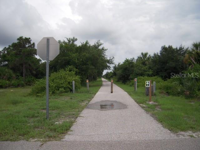 A paved trail stretches into a wooded area with a stop sign and bollards — 80 COXSWAIN CIRCLE, PLACIDA, FL