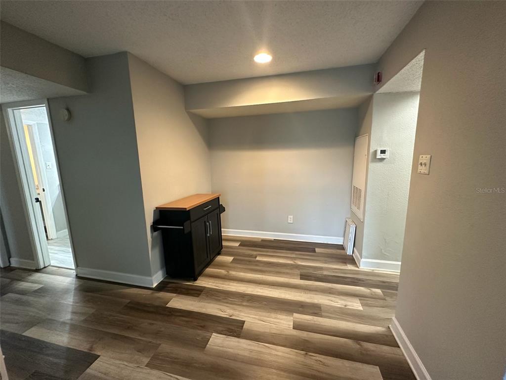 An interior view shows a room with wood-look flooring, light gray walls, and a small cabinet — 3772 IDLEBROOK CIRCLE UNIT 108, CASSELBERRY, FL