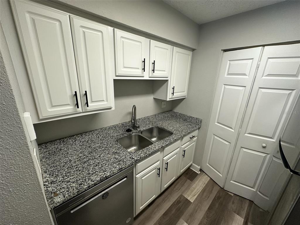 A kitchen features white cabinets, granite countertops, a double sink, and stainless steel appliances — 3772 IDLEBROOK CIRCLE UNIT 108, CASSELBERRY, FL