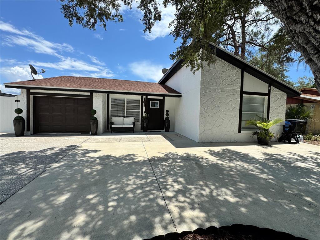 A single-story house with a white stone facade, dark trim, and a brown garage door — 10114 BRIARWICK COURT, TAMPA, FL